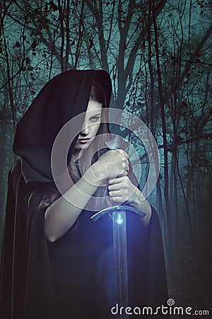 Beautiful woman with magic sword in a dark forest Stock Photo