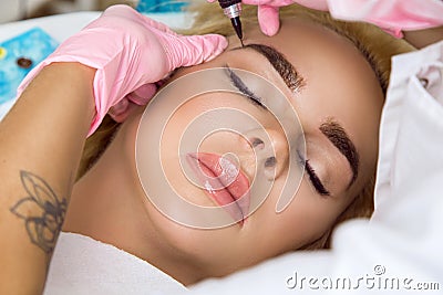 Beautiful woman with smooth, young skin, sitting in a beautician. A beautician performs modeling permanent eyebrows makings.Perman Stock Photo