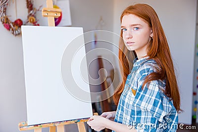 Beautiful woman painter standing near blank easel in art classroom Stock Photo