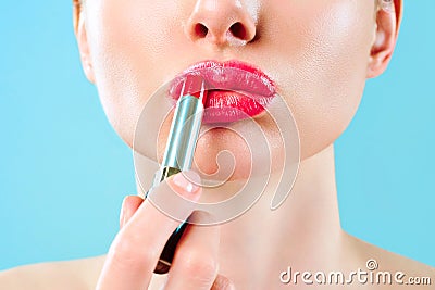 Beautiful woman paints lips with lipstick. Beautiful woman face. Makeup detail. Beauty girl with perfect skin. Red lips Stock Photo