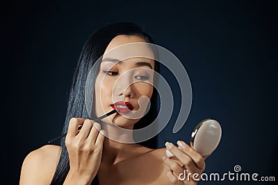 Beautiful woman paints lips with lipstick. Beautiful woman face. Makeup detail. Beauty girl with perfect skin. Red lips and nails Stock Photo