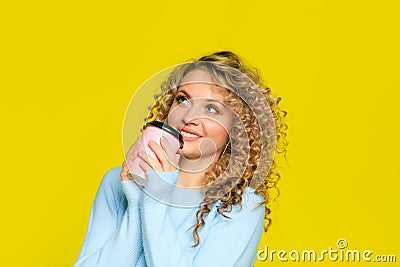 Beautiful woman portrait with curly hair on yellow background posing with coffee - Image Stock Photo