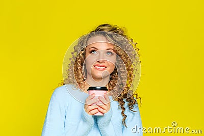 Beautiful woman portrait with curly hair on yellow background posing with coffee - Image Stock Photo