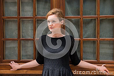 Beautiful woman posing on a background of the old wooden window. Stock Photo