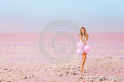 Beautiful woman with baloons on pink salt lake Stock Photo