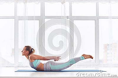 Beautiful woman practices yoga asana Salabhasana - locust pose at the yoga studio Stock Photo