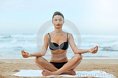 Beautiful woman practices yoga and meditates in the lotus position on th ebeach Stock Photo