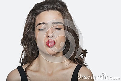 Beautiful woman puckering lips with eyes closed over gray background Stock Photo