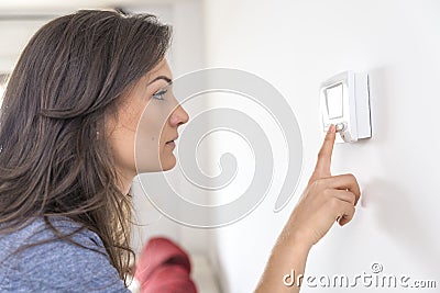 Beautiful woman push button digital thermostat at house Stock Photo