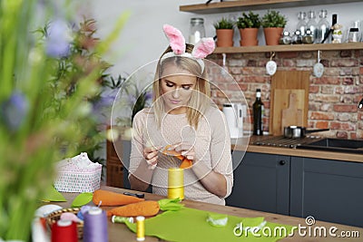 Beautiful woman in a rabbit`s ears sews Easter decorations Stock Photo