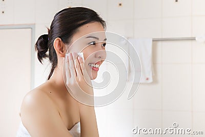 Beautiful woman removing makeup from her face in bathroom. Stock Photo