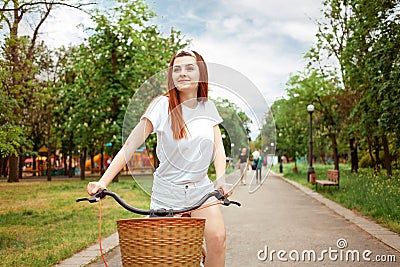 A beautiful woman rides her bike in the park. Rent transport for the day. Summer, spring. The happy girl smiles. Sport Stock Photo