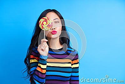 Beautiful woman send air kiss and cover her eye with colorful lollipop Stock Photo