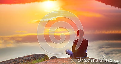 Beautiful woman sits in a pose of a lotus on high place with amazing view of the lake sunset practice yoga meditation Kundalini Stock Photo