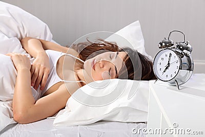 Beautiful woman sleeping alarm clock at seven Stock Photo