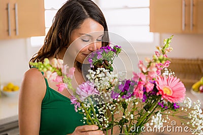 Beautiful woman smelling flowers from her lover at home on valentines day Stock Photo