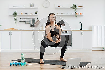 Woman holding Dachshund while squatting on mat at home Stock Photo