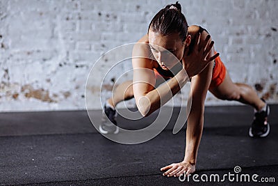 Beautiful woman in sportswear doing plank while trainnig at cross fit gym Stock Photo