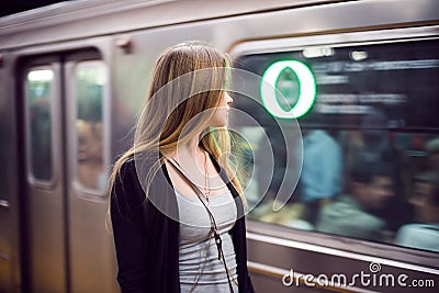 Beautiful woman stand at subway station looking at arriving metro train Stock Photo