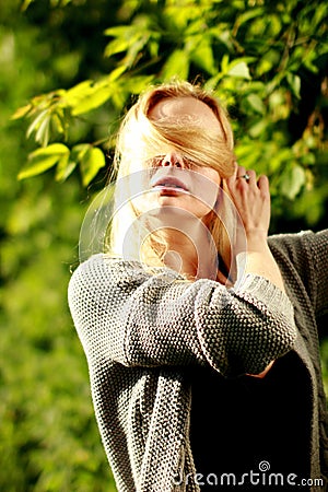 Beautiful woman in the sunny forest, covered her face with hair, fooled. Stock Photo