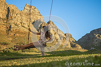 Beautiful woman swinging on a swing in nature with Table Mountain in the background. Stock Photo
