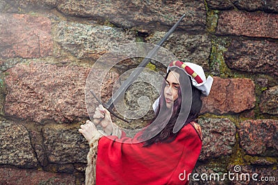 Beautiful woman swung the sword near the stone wall Stock Photo