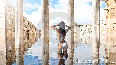 Beautiful woman taking a swim in water among ancient temple ruins Stock Photo