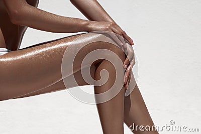 Beautiful woman tan legs. Against white wall. Stock Photo