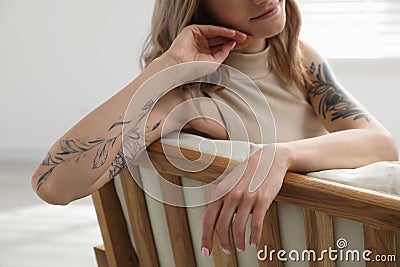 Beautiful woman with tattoos on arms resting indoors Stock Photo