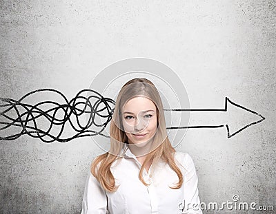 Beautiful woman is thinking about concept of business development. A huge arrow are drawn on the concrete wall. Stock Photo