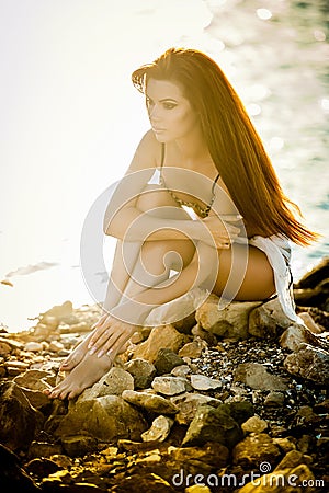Beautiful woman with veil in a bathing suit standing on the beach at sunset.Portrait of a beautiful woman in bikini on the beach Stock Photo
