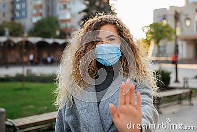 Beautiful woman in virus protection face mask showing gesture Stop Infection Stock Photo