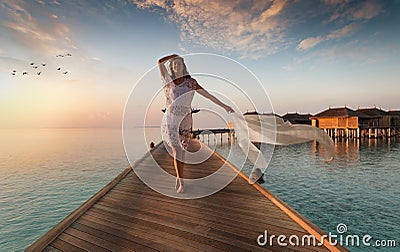 Beautiful woman walks down a wooden jetty on the Maldives Stock Photo