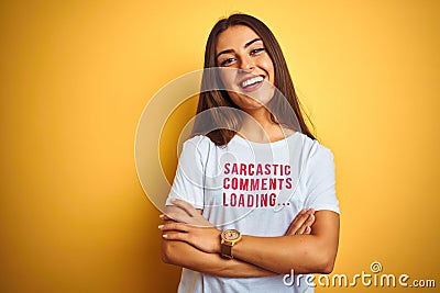 Beautiful woman wearing fanny t-shirt with irony comments over isolated yellow background happy face smiling with crossed arms Stock Photo