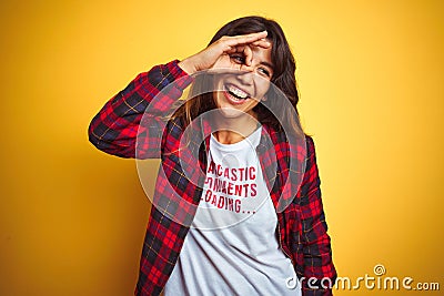 Beautiful woman wearing funny t-shirt with irony comments over isolated yellow background with happy face smiling doing ok sign Stock Photo