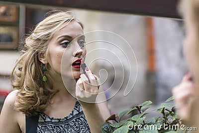 Beautiful woman wearing lipstick near the mirror. Stock Photo