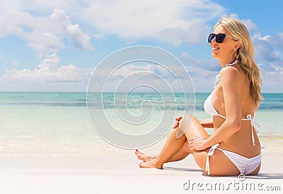 Beautiful woman in white bikini sitting on the beach Stock Photo