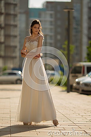 Beautiful woman in white long dress posing in the city Stock Photo