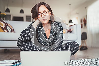 Beautiful woman writer dressed pajamas typing notebook keyboard writing novel sitting cross-legged on living room floor with a Stock Photo