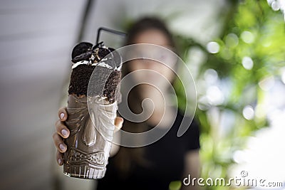 Beautiful women blurred holding a chocolate shake and cookies on a transparent glass with aboriginal design Stock Photo