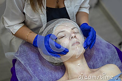 Beauty Clinic.woman gets a professional facial procedure. Beautician makes massage on a woman`s face. face renewal Stock Photo