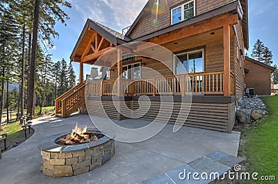 Beautiful wooden back porch with chairs on the hill and large backyard patio with fire pit and pine trees Stock Photo