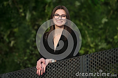 Beautiful young adult smiling woman with glasses smiling outdoors in the park. Stock Photo