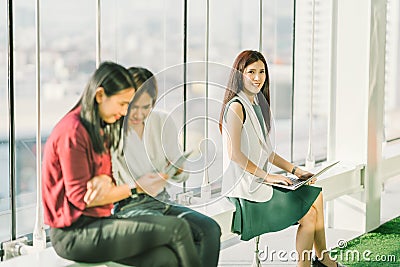 Beautiful young Asian girls using laptop notebook and digital tablet during office break at sunset, modern lifestyle concept Stock Photo