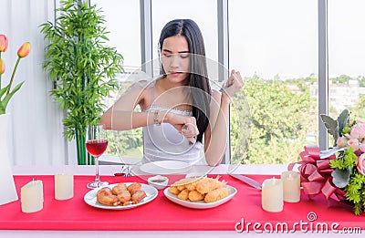 Beautiful young asian woman in white dress sitting waiting for her boyfriend in the restaurant Stock Photo