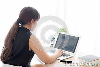 Beautiful young asian woman working and typing with laptop computer at office, businesswoman looking graph diagram analysis Stock Photo