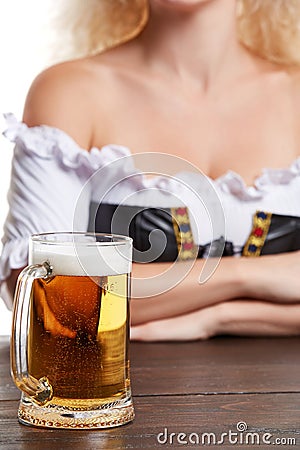 Beautiful young blond girl in traditional costume drinks out of oktoberfest beer stein. Stock Photo