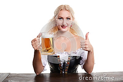 Beautiful young blond girl in traditional costume drinks out of oktoberfest beer stein. Stock Photo