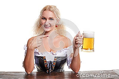 Beautiful young blond girl in traditional costume drinks out of oktoberfest beer stein. Stock Photo