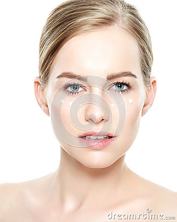 Beautiful Young Blond Woman with Face cream applied under her eyes. Facial treatment. Beauty and spa concept. Stock Photo